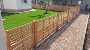 Ein moderner Garten: SaubereRandsteine, stilvolles Kiesbeet, frisch verlegter Rollrasen, ein Olivenbaum als Highlight und ein passender Holzzaun als Abschluss.