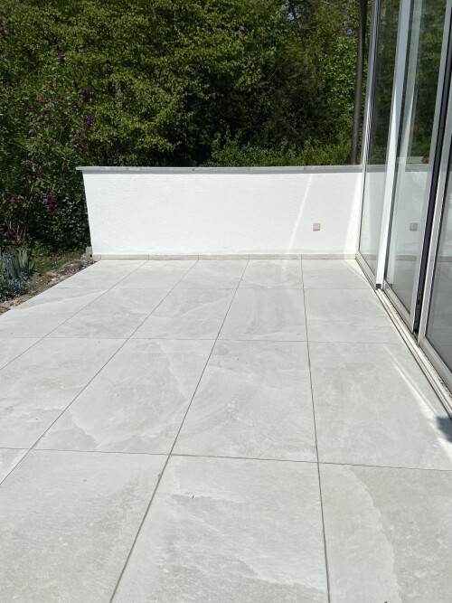 Edle Keramiksteine auf stabiler Betongrundlage und eine frisch verputzte Wand - für eine moderne und gepflegte Terrassengestaltung