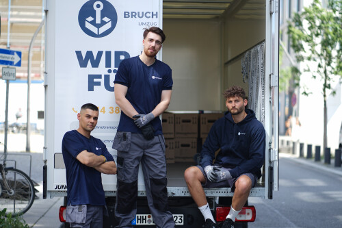 Drei Umzugshelfer sitzen hinten vor dem Umzugswagen.jpg