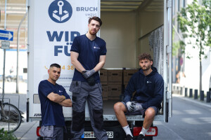 Drei Umzugshelfer sitzen hinten vor dem Umzugswagen.jpg