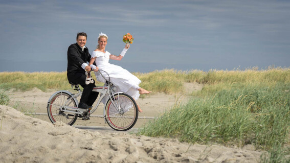 Brautpaar auf dem Fahrrad am Strand