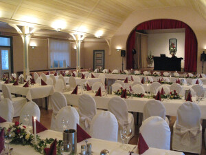 Saal eingedeckt für einen Hochzeit mit 100 Gästen. Stühle mit Hussen.