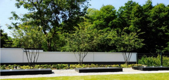 Modernes Wasserspiel aus polierten Granitblöcken vor minimalistischer Bepflanzung