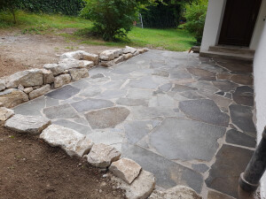 Terrasse mit Porphyrplatten und Sandsteinmauer